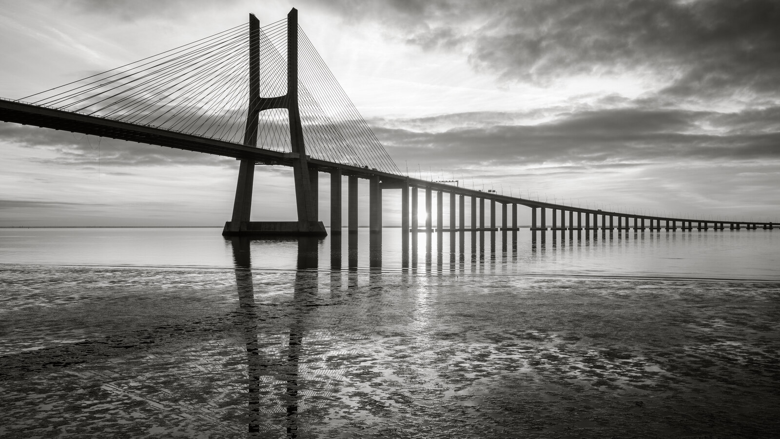 A long bridge spanning open water to the horizon at sunrise